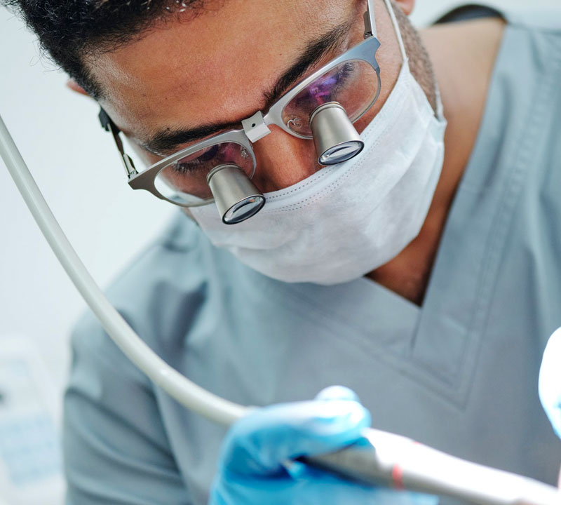 Clinician wearing magnifying loupes and a surgical mask performing a procedure