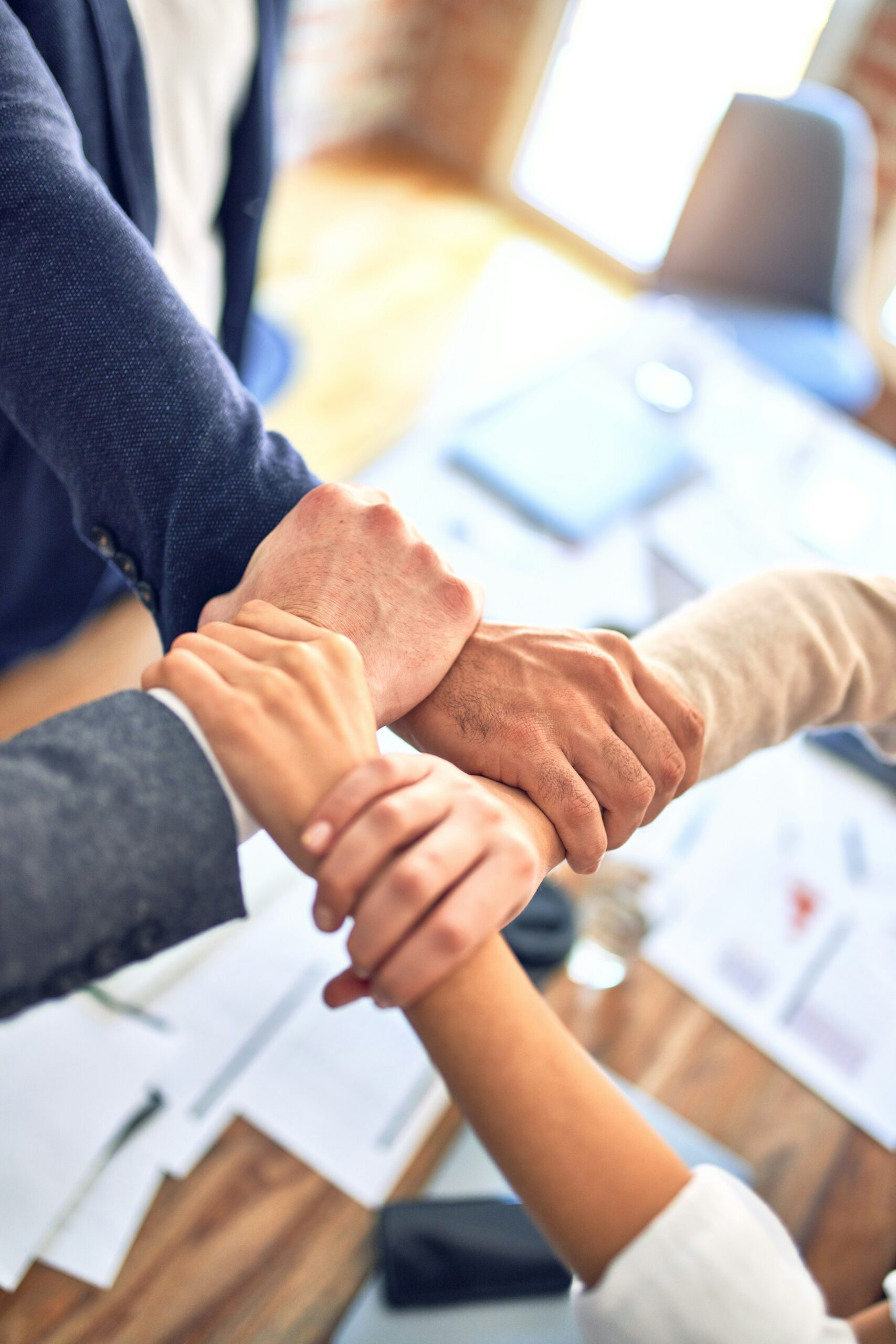 Group of colleagues joining hands together in a team huddle
